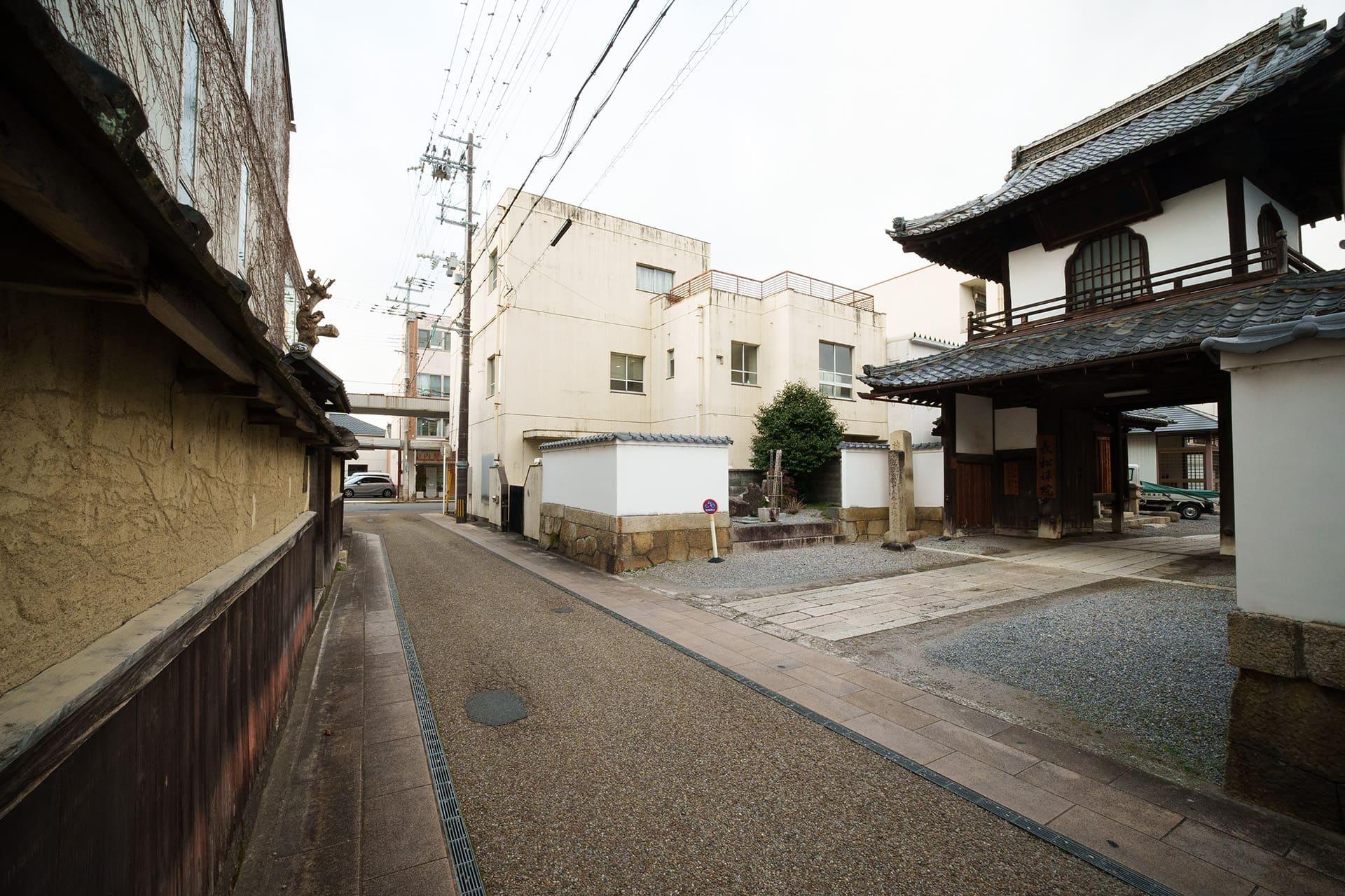 少し下がると、土壁の向かいに当時から変わっていないであろうお寺があるのが分かる（2026年1月）